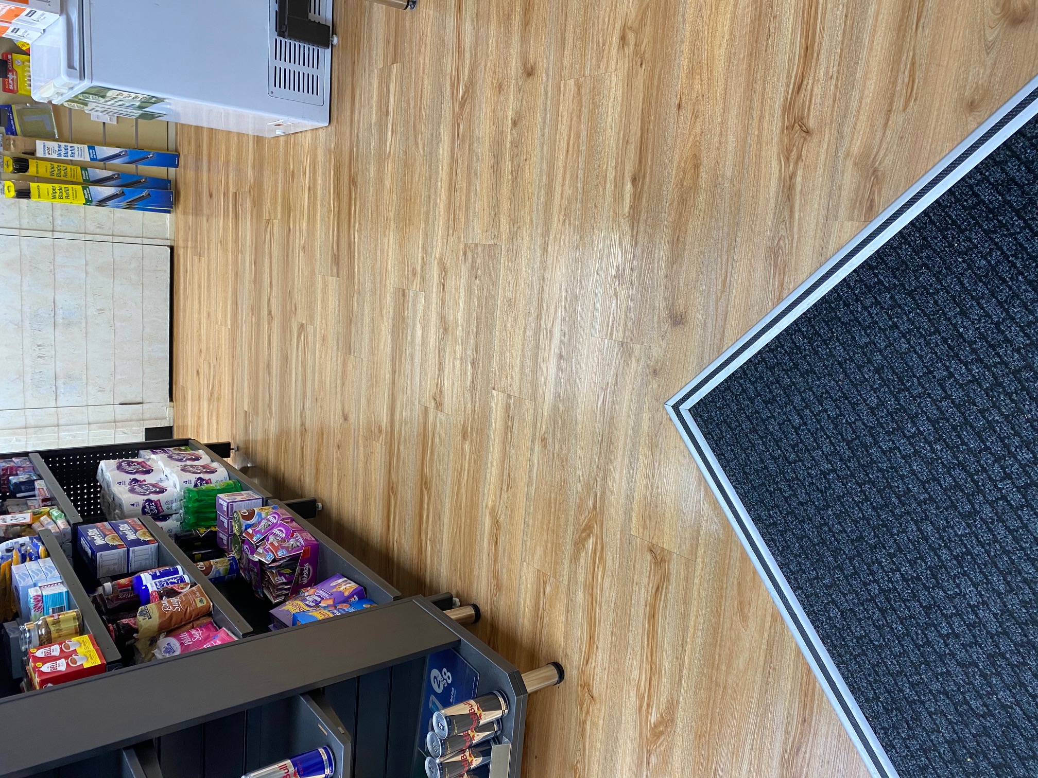 BP Northcote: Oak-look plank floor through a convenience store, with a dark entry mat at the door
