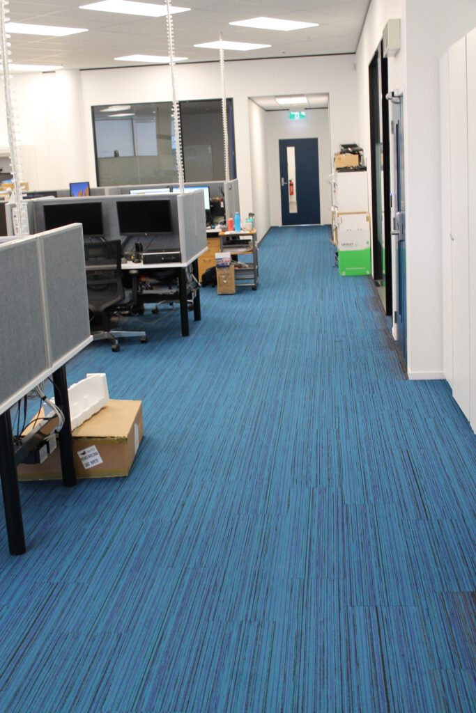 Briscoes HQ Morningside: Grey carpet in the open-plan office and grey timber-look planks in the kitchen and corridor
