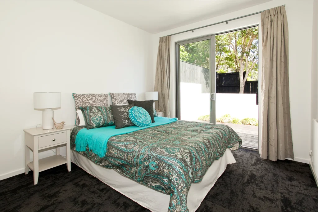 Kittiwake: Dark carpet in a bedroom with pale timber-look floor in the living area
