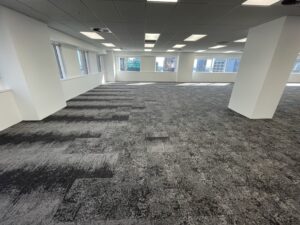 Open-plan office floor with grey carpet tile flooring and columns