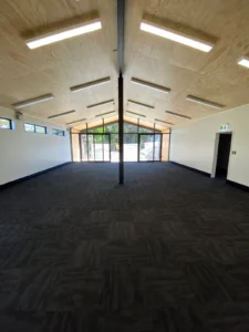 Large empty room with dark carpet tile flooring and high ceiling
